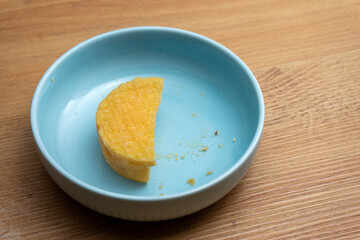 Half-eaten Alentejo sheep's cheese on a blue plate, highlighting the creamy texture and natural rind