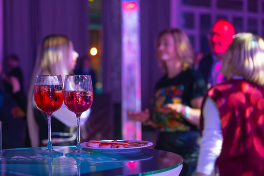 Wine glasses on table with people in blurred background at social event, creating elegant and lively atmosphere.