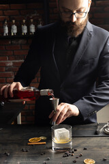 The process of preparing an alcoholic cocktail by a bartender. Winter and New Year cocktails. Bar, nightlife. Red drink.