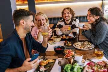 Friends gathered in a restaurant to eat delicious food, talk, drink and hang out.