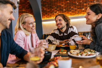 Friends gathered in a restaurant to eat delicious food, talk, drink and hang out.