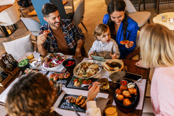 Family and friends gathered in a restaurant to eat delicious food, talk, drink and hang out.