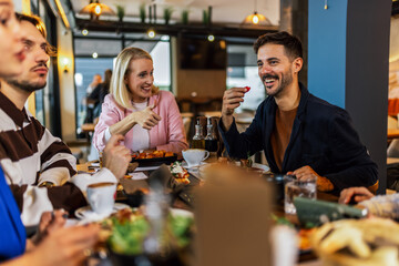 Family and friends gathered in a restaurant to eat delicious food, talk, drink and hang out.
