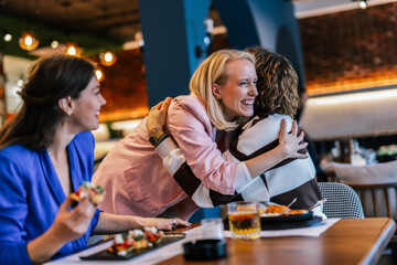Friends saw each other at the restaurant and stopped by to say hello.