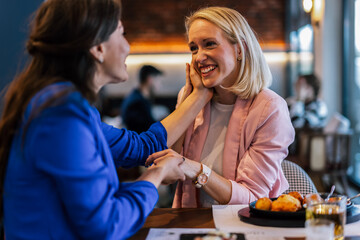 Smiling lesbian couple talking to each other at restaurant