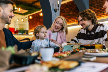 Family and friends gathered in a restaurant to eat delicious food, talk, drink and hang out.
