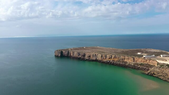 Aerial view of Sagres Cape. View of Sagres Lighthouse, at left. Sagers Fortress at right side. Famous travel destination in Algarve Region, South of Portugal. High cliffs. Drone panning right.