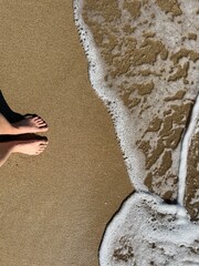 two feet in the golden sand on the beach in summer waiting for the waves of the ocean water