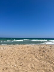 a golden coastline with small waves and blue sky in summer