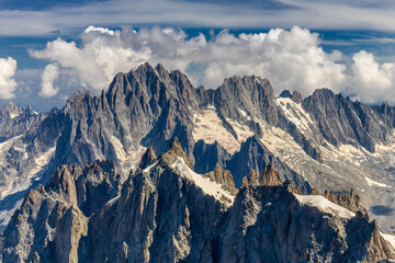 Snow mountains view in the Alps from Aiguille du Midi summit. Rocky mountain peaks scene covered with snow and ice of huge alpine glacier on the massive du Mont Blanc range in Chamonix