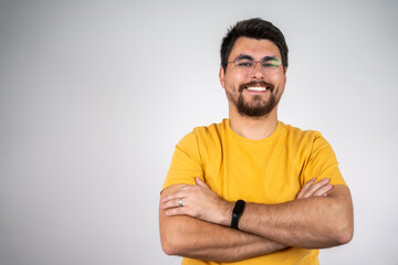 Fototapeta premium Portrait of handsome smiling young man with folded arms. Smiling joyful cheerful men with crossed hands studio shot. Isolated on gray background