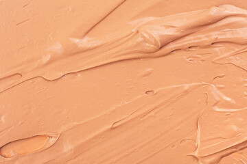 Background made of liquid foundation. Creamy foundation texture. Beige makeup smear of creamy foundation. Foundation swatch texture.