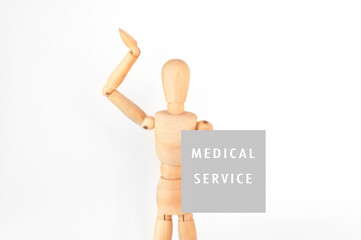 Wooden figure is holding a sign that says Medical Service