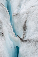 close up glacier snow and ice with crack in the middle. Black vulcanic sand on top the snow. Icelandic glacier detail. 