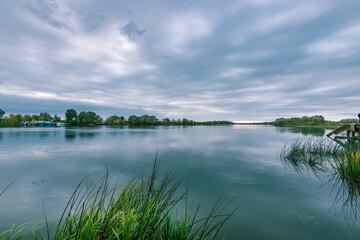 A calm lake with a few trees in the background