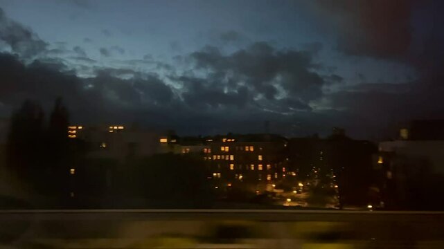 View from the fast train window over the Berlin cityscape with multiple homes and beautiful sunset colored sky. Houses in the suburbs. A view through the window of a moving train. 