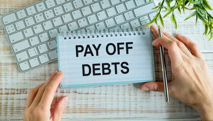 Work smarter text Pay Off Debts on white sheet with pen, keyboard and tables.