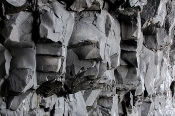 close up black lava rock formations on the black beach in iceland. Basalt rock stone. Natural material. Geology scene. Volcanic detail