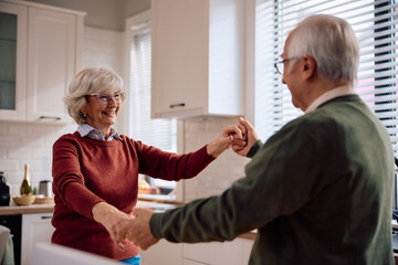 Happy elderly couple dancing at home.