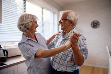 Happy senior couple dancing at home.