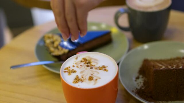 latte sprinkles woman pours caramel syrup over a pumpkin latte and sprinkle with cinnamon.