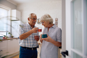 Obraz premium Smiling senior woman smelling fresh tea her husband made at home.