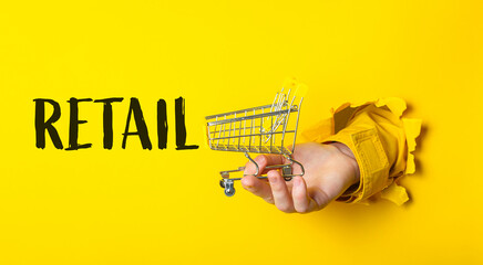 Hand holding a shopping cart with the word retail above it