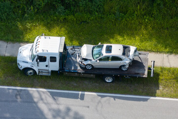 Car crash site with tow truck loading destroyed vehicle on American street. Emergency services...