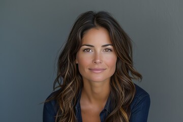 Fototapeta premium Confident Brunette Businesswoman Smiling Against a Gray Background