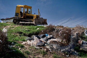  bulldozer stands on a grassy, debris-covered hill.