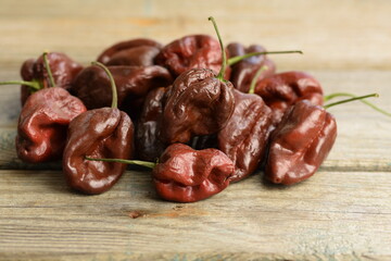 Brown Habanero peppers on wooden background, Habanero Chocolate, selective focus, bokeh, red habanero background, pepper background, space for text, copy space.