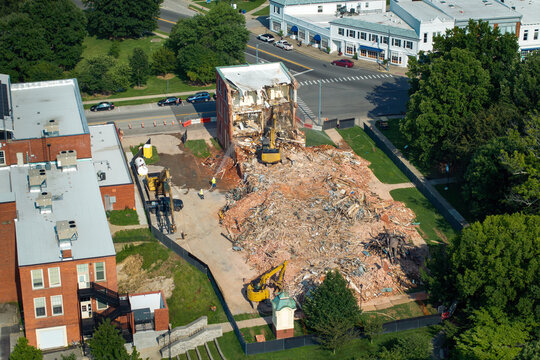 Old building demolition site. Construction excavator tearing down obsolete brick walls of Historic Edwards Building in Berea, Kentucky, USA. City planning concept
