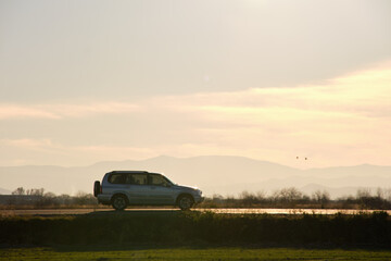 Fototapeta premium SUV car driving fast on intercity road at sunset. Highway traffic in evening