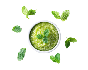 a bowl of green sauce surrounded by leaves