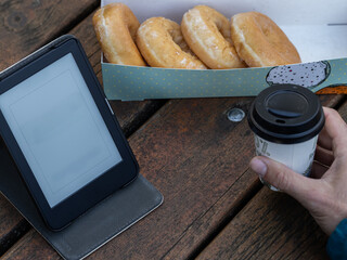 top view of a man having a takeaway coffee and reading in an e-book in a park