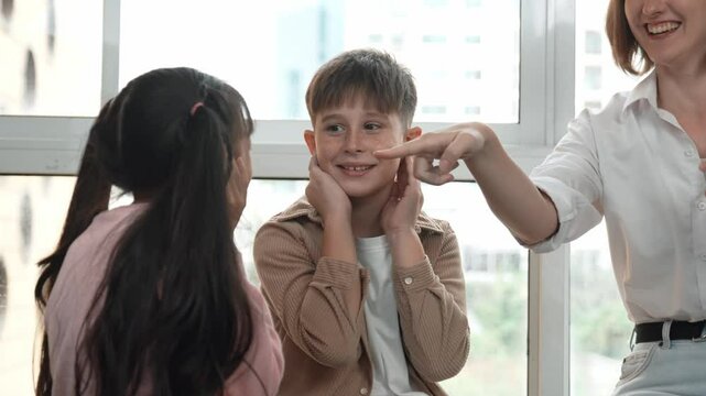 Diverse student learning about body organ while playing with teacher. Multicultural learner sitting around care taker while touching ear in STEM science class. Creative activity concept. Erudition.