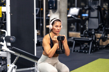 Fototapeta premium Concentrated fit woman training with weights in the gym.