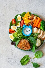 Vegetable plate with meat, fish and eggs. Complete diet for the day. Time to eat healthy foods. Eating by the hour. Health concept, copy space