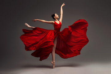 Ballerina. Young graceful woman ballet dancer, dressed in professional outfit, shoes and red weightless skirt is demonstrating dancing skill. Beauty of classic ballet.