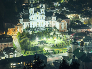 night aerial shot of white catholic cathedral in night city illumination