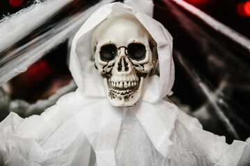 A ghost draped in a white sheet hangs from the ceiling, creating an eerie atmosphere in the dimly...
