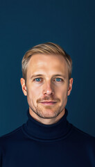 Fototapeta premium Man with Light Brown Hair in Dark Blue Turtleneck Sweater on Solid Blue Background