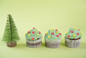 Chocolate cupcakes with green whipped cream topping in the form of Christmas tree for Christmas holidays