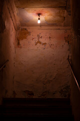 A single lightbulb shining above a creepy dark staircase