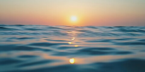 The sun sets over the horizon casting a warm glow on the rippling water.