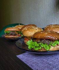 burgers home made at home on the table from beef, cheese and vegetables on an old wooden table. Fatty junk food close-up.