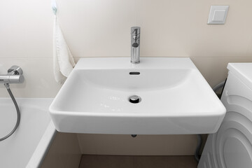 White sink with silver tap in light bathroom