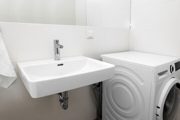 White sink and washing machine in light bathroom