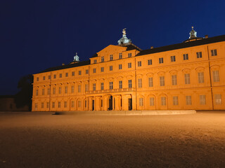 Fototapeta premium A large building with a yellow facade is lit up at night