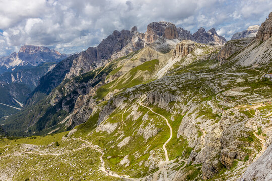 Sunny day in the Dolomites. Rocky mountain peaks of Dolomiti Alps in summer under the blue sky with some clouds prominent mountain summits landscape and stunning views of the alpine range and meadow - Powered by Adobe